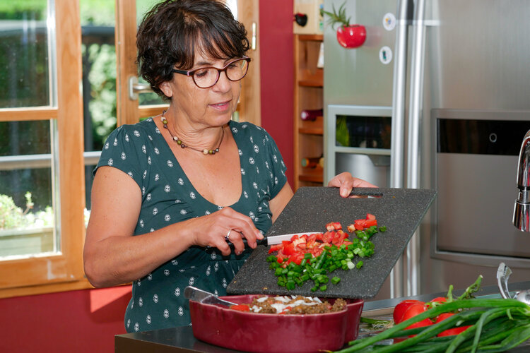Woman chopping red a green pepper on a cutting board and putting them in a dish - Neuroplasticity After Brain Injury: 8 Proven Ways to Support Recovery